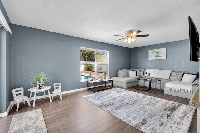 living room featuring a textured ceiling, ceiling fan, and dark wood-type flooring