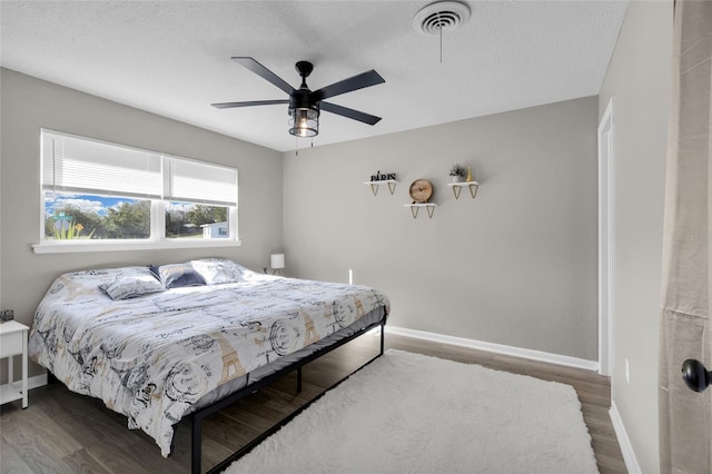 bedroom with a textured ceiling, dark hardwood / wood-style flooring, and ceiling fan