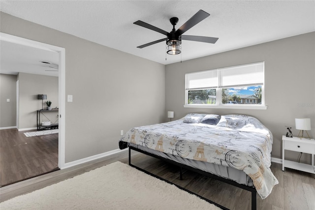 bedroom with wood-type flooring, a textured ceiling, and ceiling fan