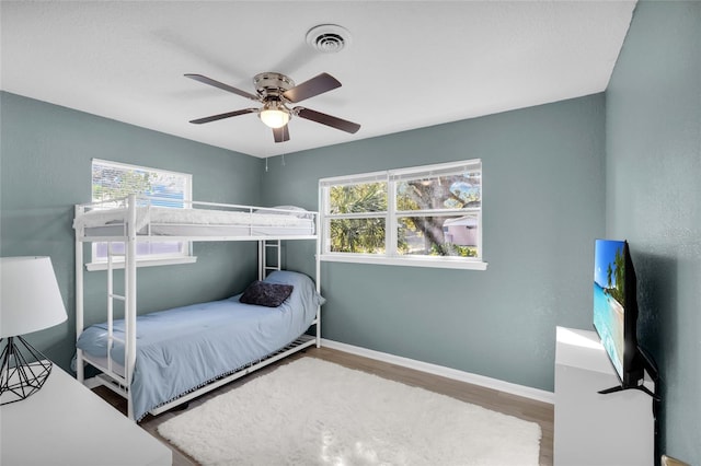 bedroom featuring multiple windows, ceiling fan, and hardwood / wood-style floors