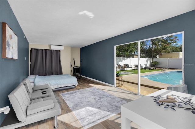 bedroom featuring wood-type flooring, access to outside, and a wall mounted AC