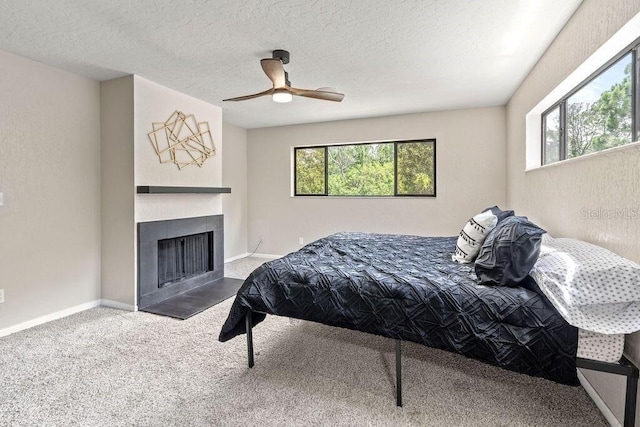 carpeted bedroom with a fireplace, a textured ceiling, and ceiling fan