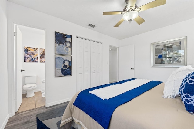 bedroom featuring hardwood / wood-style floors, ceiling fan, connected bathroom, and a closet