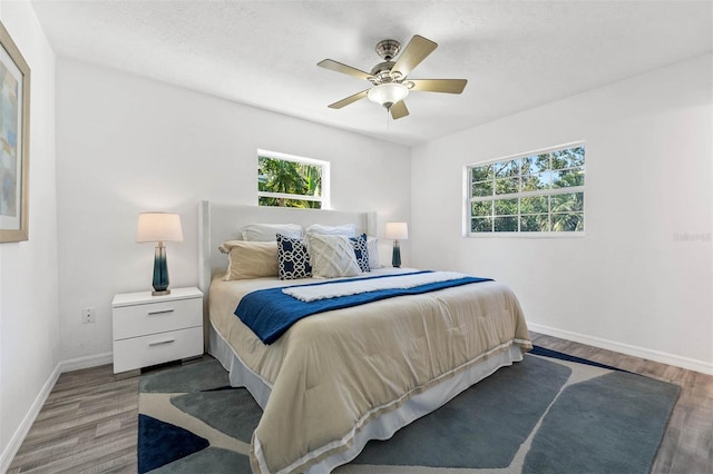 bedroom featuring ceiling fan, wood-type flooring, and a textured ceiling