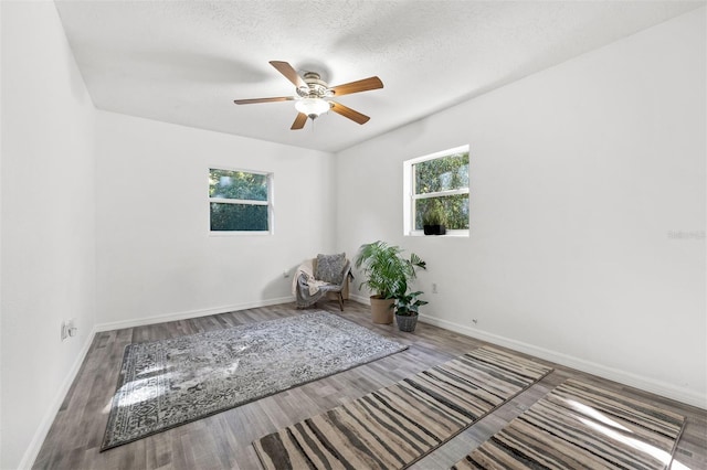 unfurnished room featuring ceiling fan, a healthy amount of sunlight, wood-type flooring, and a textured ceiling