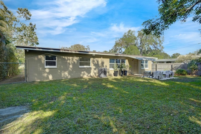 rear view of property featuring cooling unit and a lawn