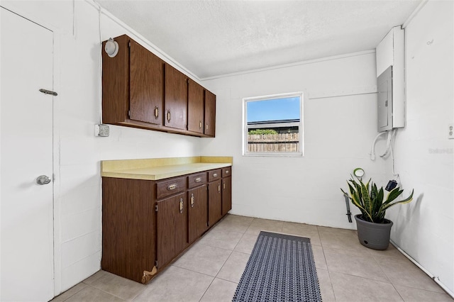 laundry area featuring electric panel, light tile patterned flooring, and a textured ceiling