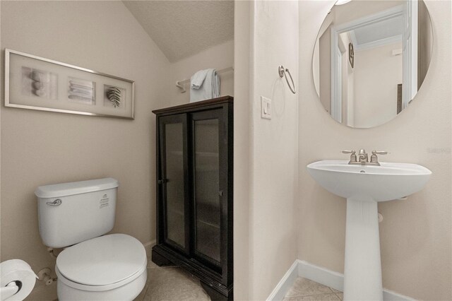 bathroom with tile patterned floors, toilet, lofted ceiling, and a textured ceiling