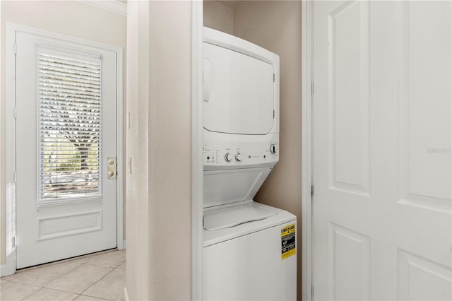 laundry room with light tile patterned flooring and stacked washing maching and dryer