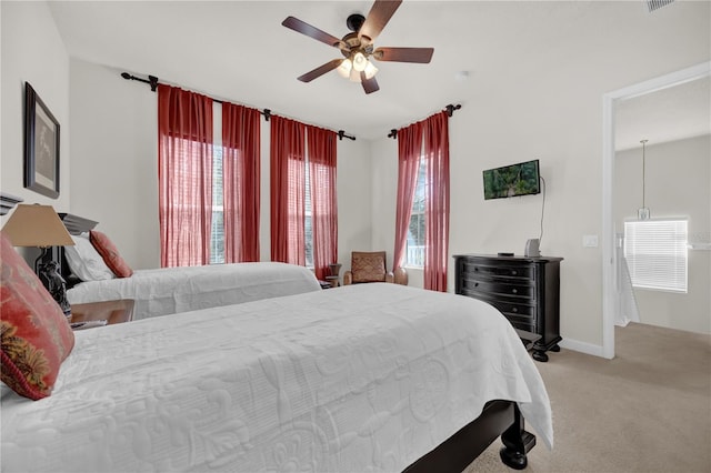 bedroom featuring ceiling fan, light colored carpet, and multiple windows