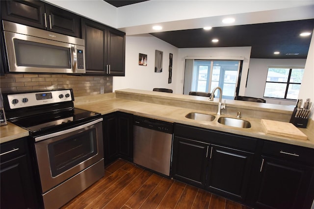 kitchen with sink, tasteful backsplash, dark hardwood / wood-style flooring, kitchen peninsula, and stainless steel appliances