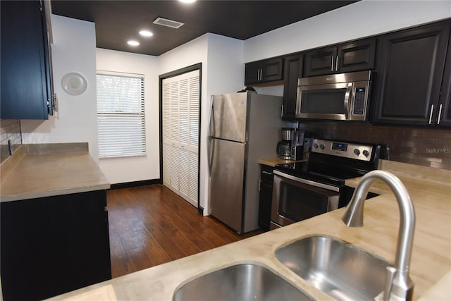 kitchen with appliances with stainless steel finishes, tasteful backsplash, dark wood-type flooring, and sink