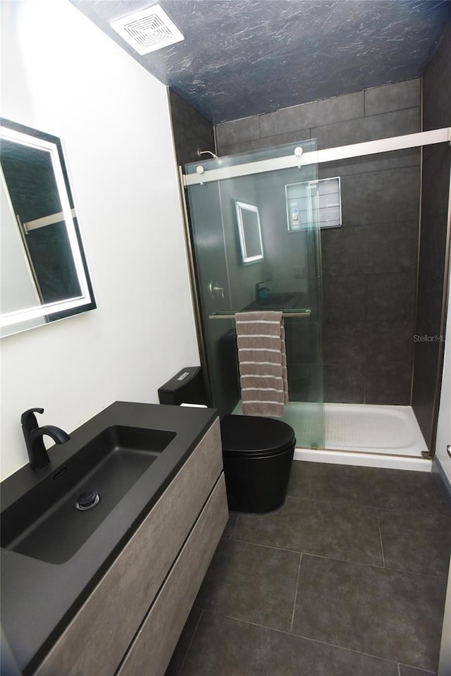 bathroom with tile patterned flooring, vanity, an enclosed shower, and toilet