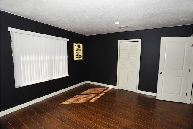 unfurnished room with dark hardwood / wood-style flooring and a textured ceiling