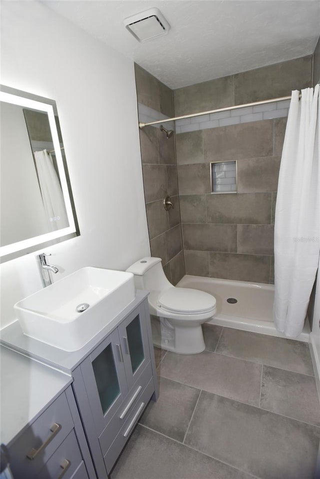 bathroom with tile patterned floors, curtained shower, vanity, and toilet