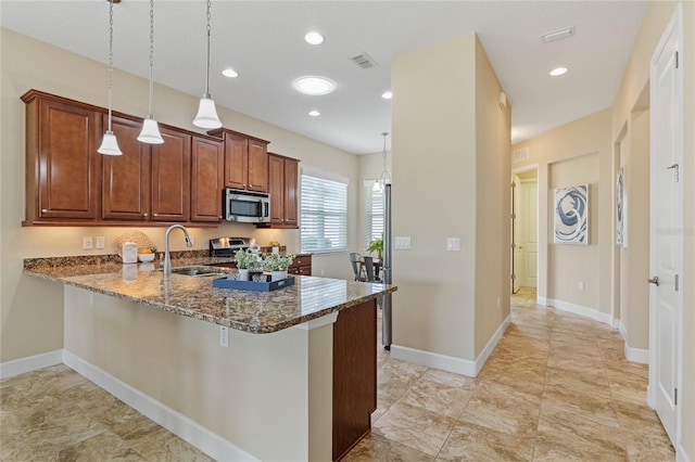 kitchen featuring sink, hanging light fixtures, stainless steel appliances, kitchen peninsula, and dark stone counters