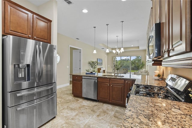 kitchen with sink, light stone counters, a chandelier, decorative light fixtures, and appliances with stainless steel finishes