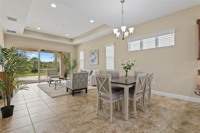 dining area with a chandelier and a raised ceiling