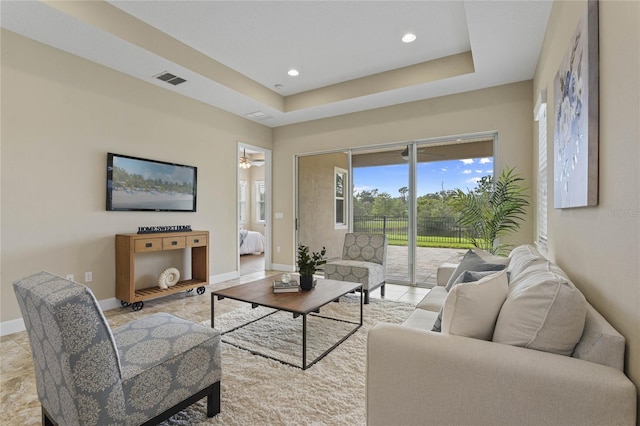 living room featuring ceiling fan and a raised ceiling