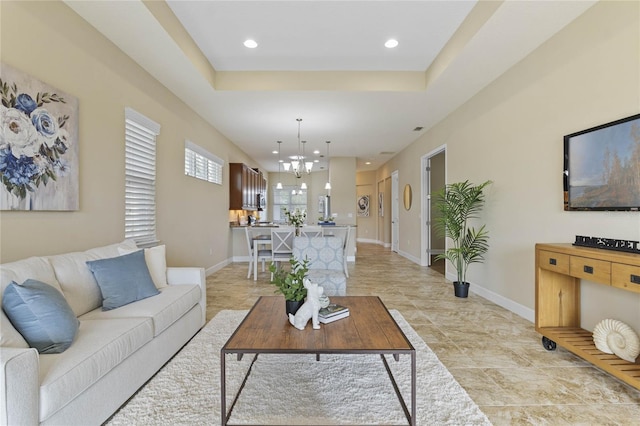 living room with a tray ceiling and a notable chandelier