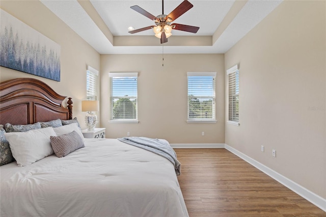 bedroom with a tray ceiling, ceiling fan, and hardwood / wood-style floors