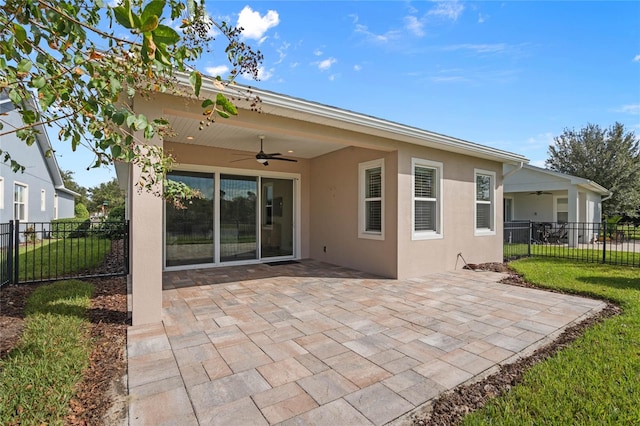 back of property with a lawn, ceiling fan, and a patio