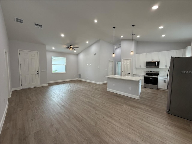 kitchen featuring white cabinets, a center island, stainless steel appliances, and vaulted ceiling