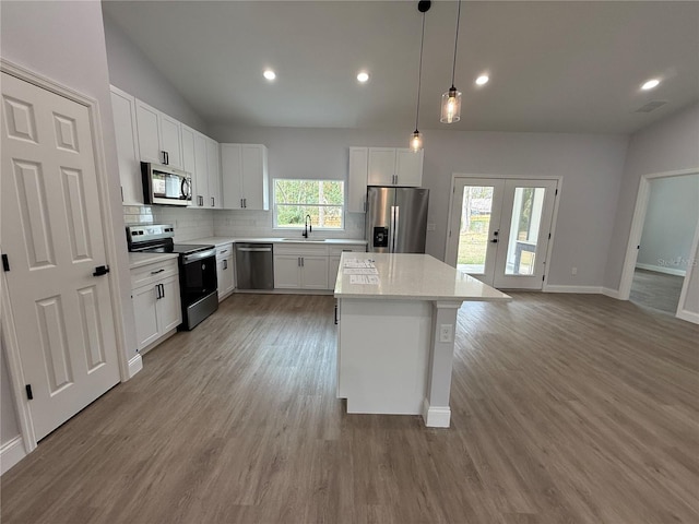 kitchen featuring appliances with stainless steel finishes, light wood-type flooring, white cabinetry, and a kitchen island