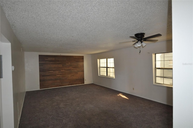 spare room with ceiling fan, dark carpet, and a textured ceiling