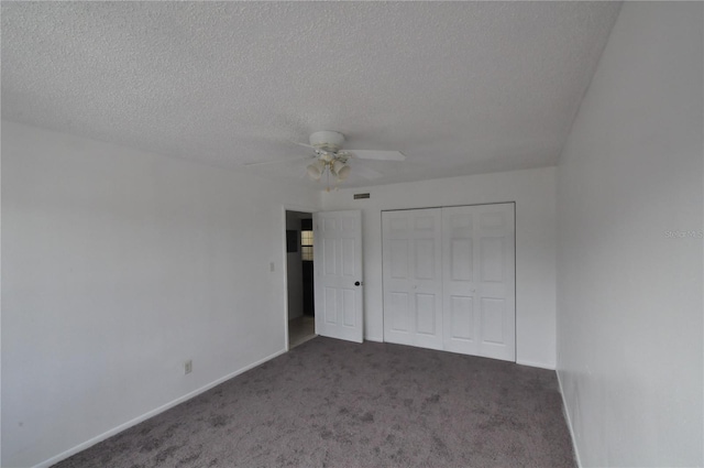 unfurnished bedroom featuring ceiling fan, dark carpet, a textured ceiling, and a closet