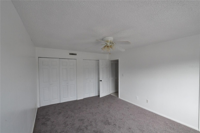 unfurnished bedroom featuring ceiling fan, carpet floors, a textured ceiling, and two closets