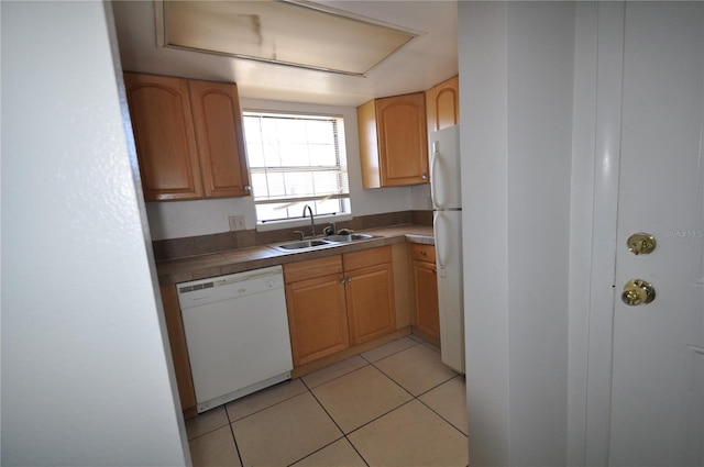 kitchen with light tile patterned floors, white appliances, and sink