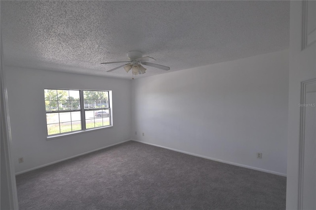 empty room featuring ceiling fan, dark carpet, and a textured ceiling