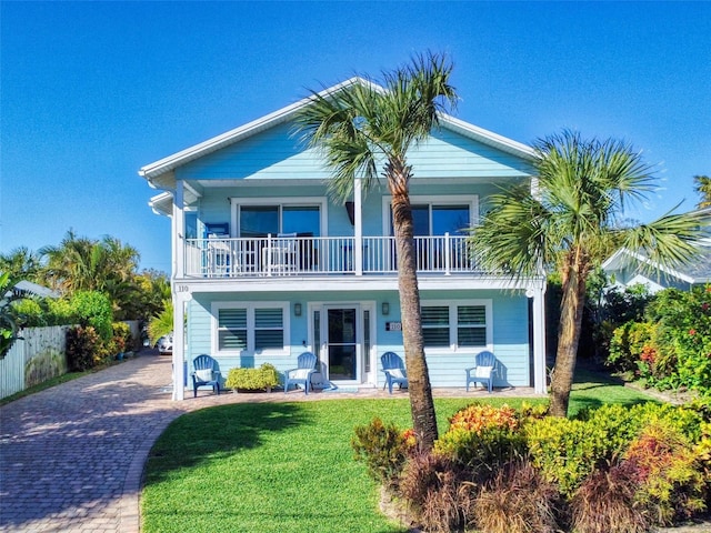 raised beach house featuring a balcony and a front yard