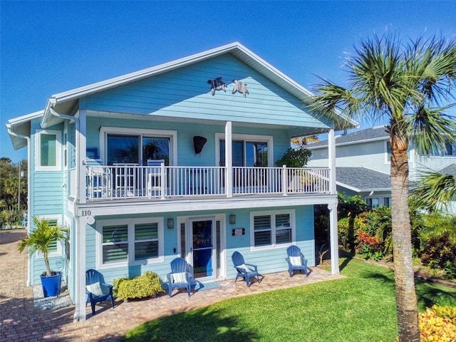 coastal inspired home with a balcony and a front lawn