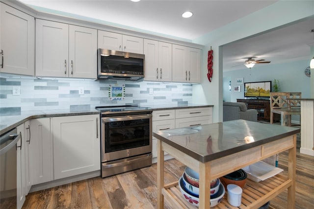 kitchen with decorative backsplash, hardwood / wood-style floors, white cabinets, and appliances with stainless steel finishes