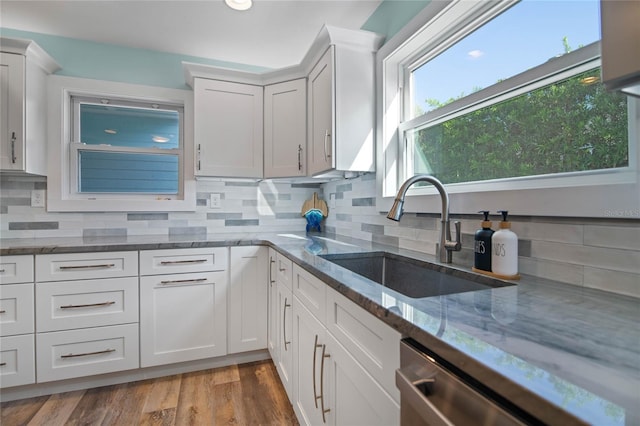 kitchen with white cabinets, light stone counters, and sink