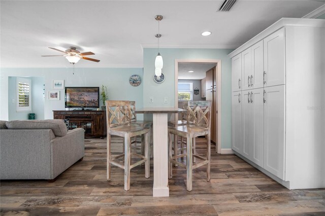 dining area with dark hardwood / wood-style floors, ceiling fan, and ornamental molding