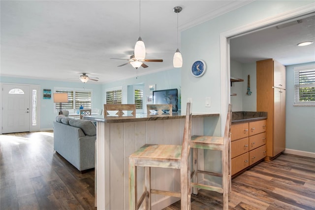 kitchen featuring a kitchen bar, kitchen peninsula, dark hardwood / wood-style floors, and ornamental molding