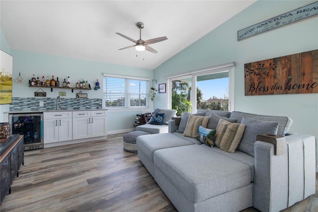 living room with beverage cooler, ceiling fan, hardwood / wood-style flooring, wet bar, and lofted ceiling