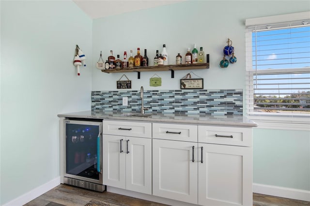 bar featuring sink, wine cooler, dark hardwood / wood-style floors, light stone counters, and white cabinetry