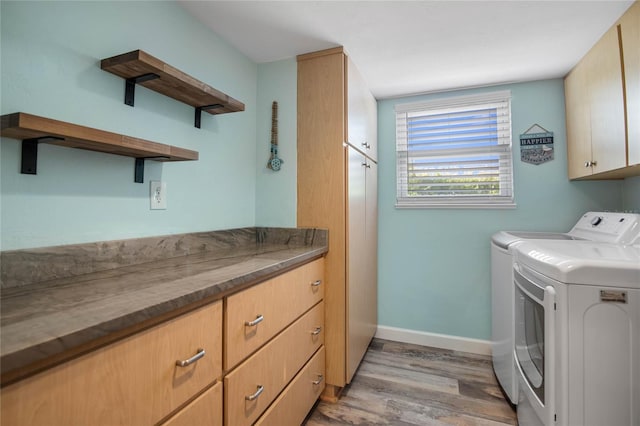 laundry area with washer and clothes dryer, cabinets, and light hardwood / wood-style flooring