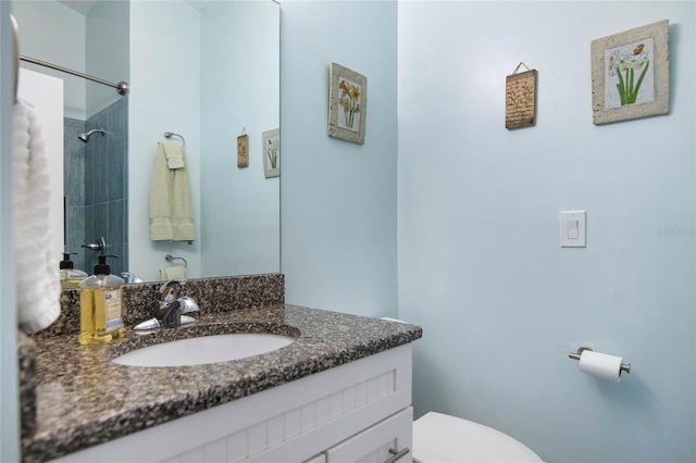 bathroom with a tile shower, vanity, and toilet