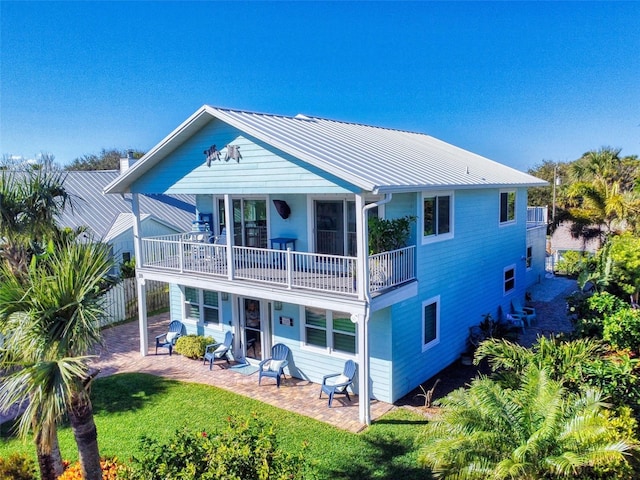 rear view of house with a lawn, a patio area, and a balcony