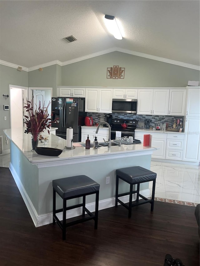 kitchen featuring white cabinetry, dark hardwood / wood-style floors, crown molding, a breakfast bar, and appliances with stainless steel finishes