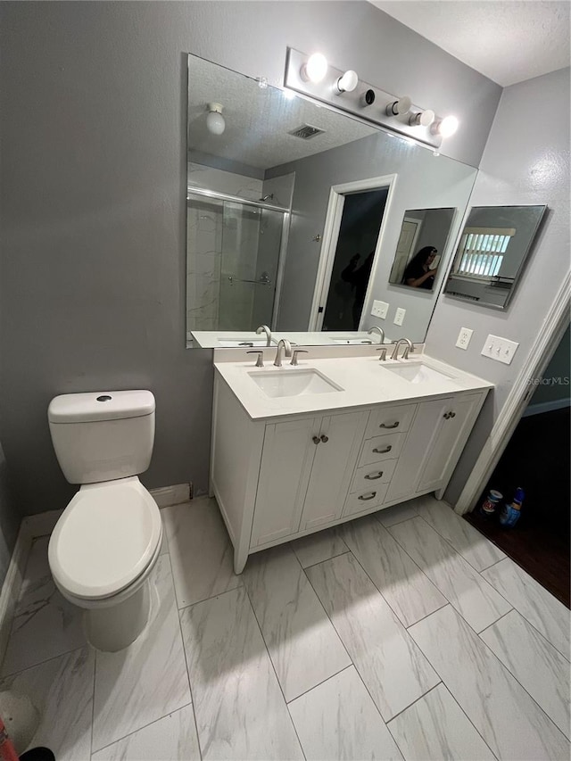 bathroom featuring toilet, vanity, a textured ceiling, and walk in shower