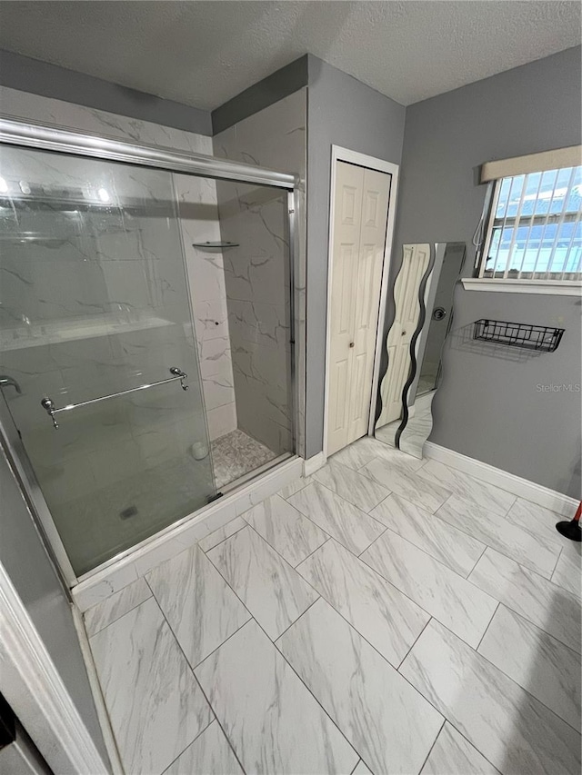 bathroom with a shower with shower door and a textured ceiling