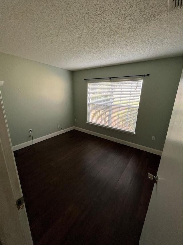 unfurnished room with a textured ceiling and dark hardwood / wood-style flooring