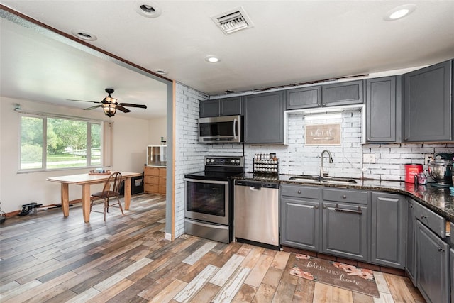 kitchen featuring gray cabinetry, ceiling fan, sink, stainless steel appliances, and hardwood / wood-style floors