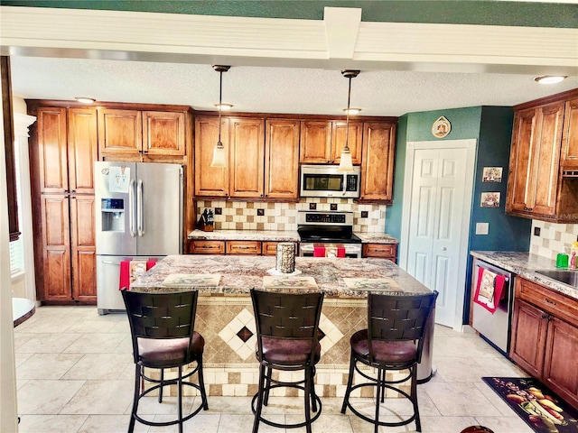 kitchen featuring stainless steel appliances, light stone counters, pendant lighting, a breakfast bar area, and a kitchen island